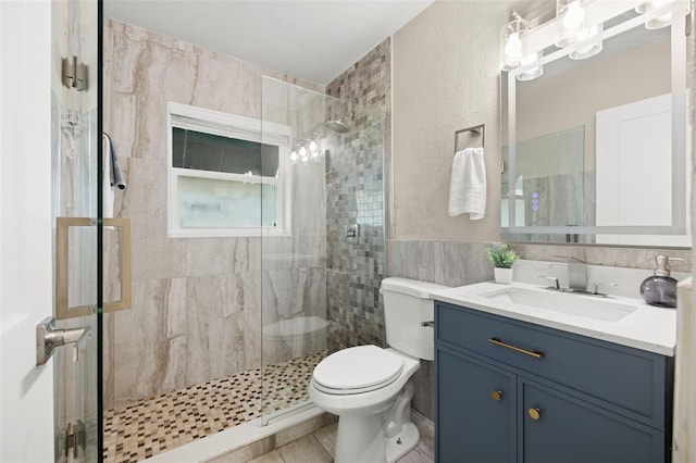 bathroom with tile walls, toilet, vanity, a stall shower, and a textured wall