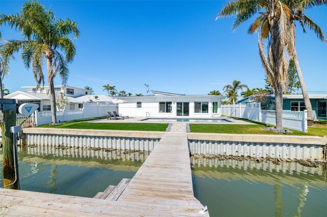 dock area with a fenced backyard, a lawn, a water view, and a patio area