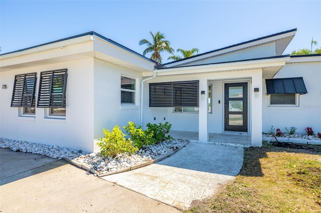 doorway to property featuring stucco siding