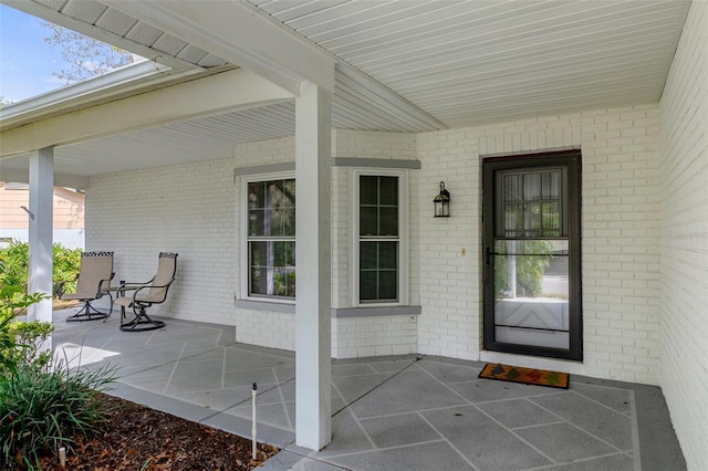 entrance to property with a porch and brick siding