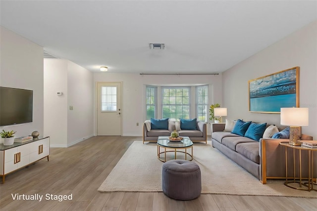 living room with baseboards, visible vents, and wood finished floors
