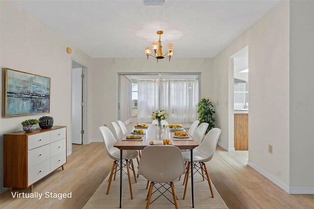dining area featuring baseboards, visible vents, light wood-style floors, and an inviting chandelier