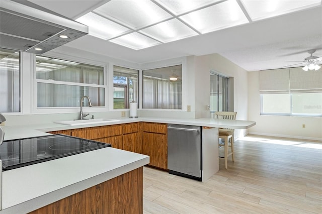 kitchen with brown cabinetry, light countertops, a sink, and dishwasher