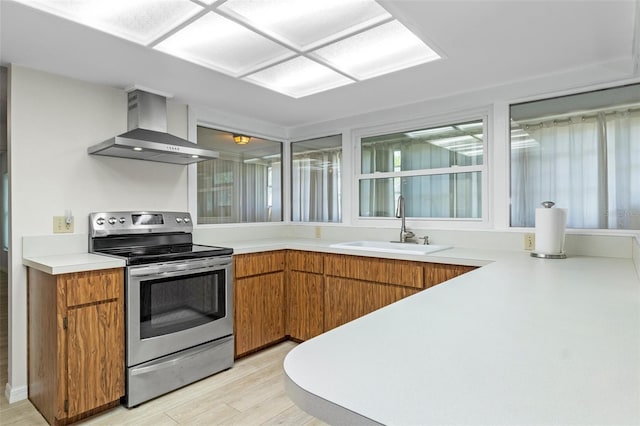 kitchen with wall chimney exhaust hood, electric range, light countertops, and a sink