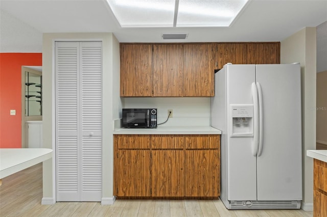 kitchen with visible vents, light countertops, black microwave, and white fridge with ice dispenser