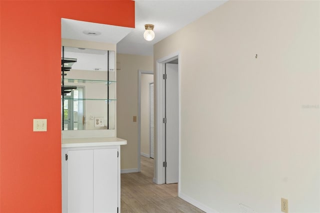 corridor with baseboards and light wood finished floors
