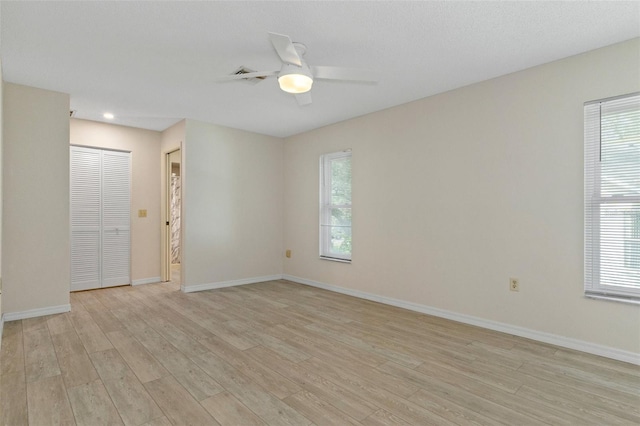 unfurnished room featuring light wood finished floors, baseboards, ceiling fan, and a healthy amount of sunlight