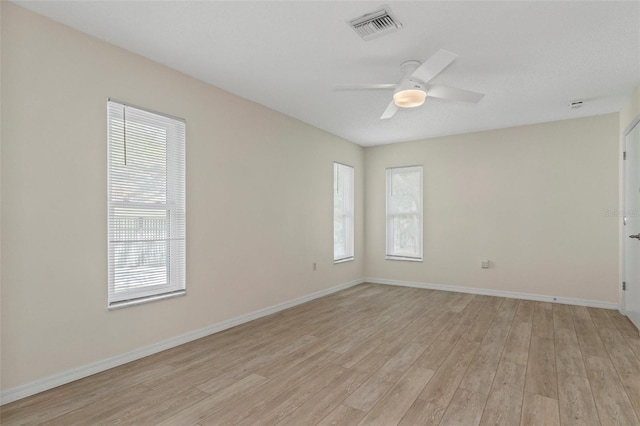 empty room with a ceiling fan, baseboards, light wood finished floors, and visible vents