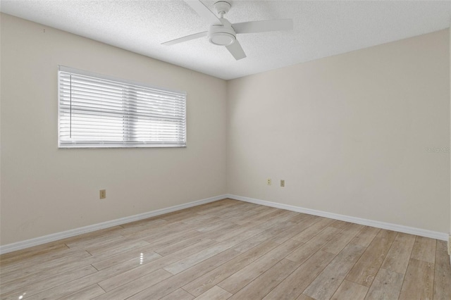 empty room with baseboards, a textured ceiling, a ceiling fan, and light wood finished floors
