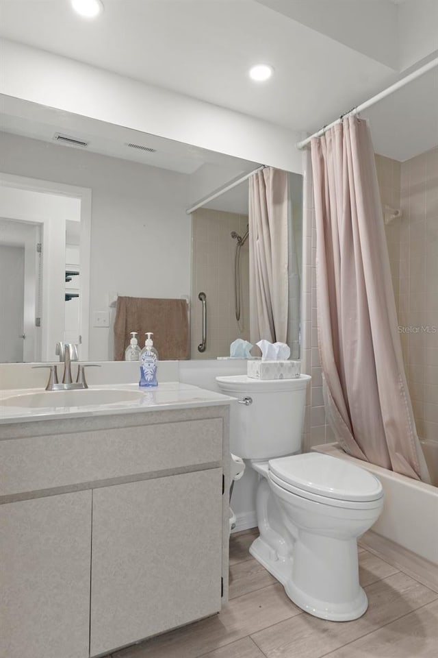 full bathroom with visible vents, wood finished floors, toilet, vanity, and shower / tub combo with curtain
