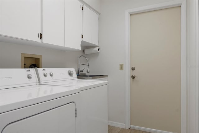 clothes washing area with a sink, cabinet space, washing machine and dryer, and baseboards