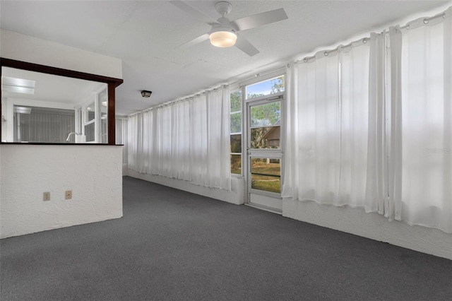 unfurnished room with a textured ceiling, carpet floors, ceiling fan, and a textured wall
