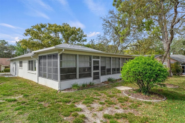 rear view of property featuring a lawn and a sunroom