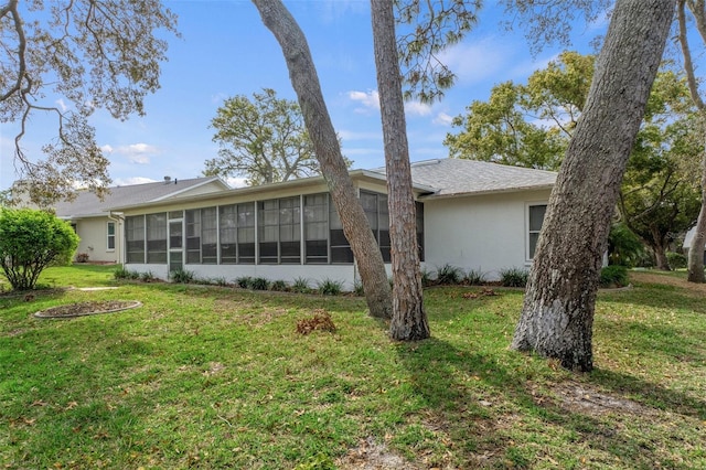 rear view of property with a lawn, a sunroom, and stucco siding