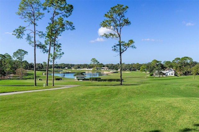 view of home's community with a water view, view of golf course, and a yard