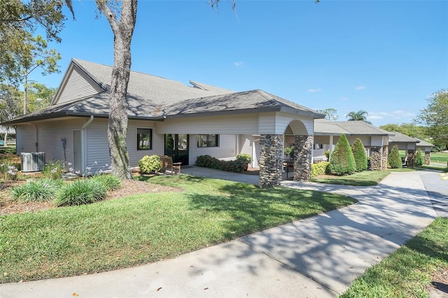 view of front of house with concrete driveway, a shingled roof, and a front lawn