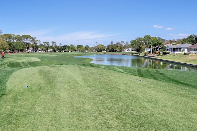 view of home's community with view of golf course, a water view, and a yard