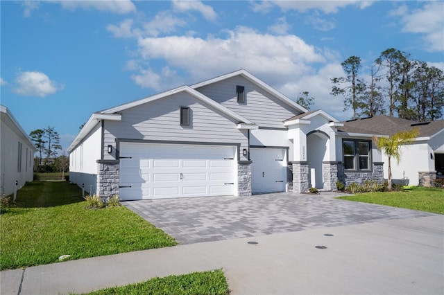 view of front of property with stone siding, decorative driveway, a front lawn, and an attached garage
