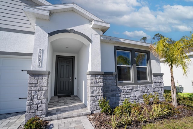 entrance to property featuring stone siding and stucco siding