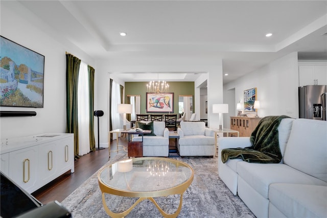 living room featuring a raised ceiling, a notable chandelier, dark wood-type flooring, and recessed lighting