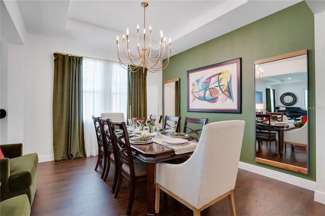 dining space with an inviting chandelier, a tray ceiling, baseboards, and wood finished floors