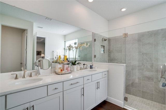 full bath with double vanity, visible vents, tiled shower, and a sink