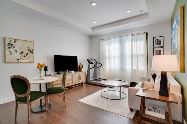 living area featuring dark wood-style floors, baseboards, recessed lighting, and a raised ceiling