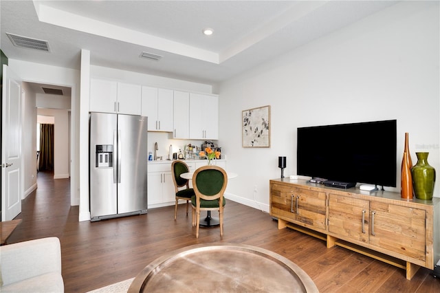 living room featuring dark wood-type flooring, baseboards, and visible vents