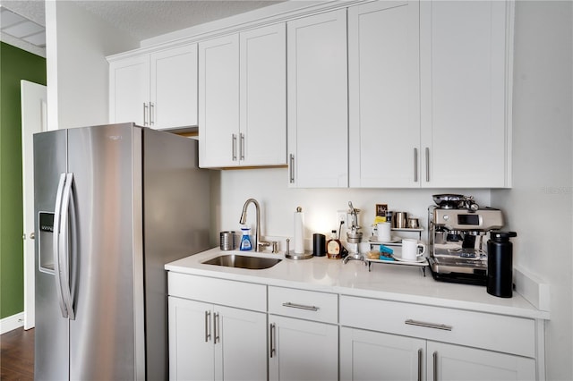 kitchen with light countertops, white cabinets, a sink, stainless steel refrigerator with ice dispenser, and dark wood-style floors