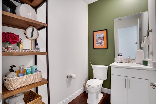 half bathroom featuring baseboards, toilet, vanity, and wood finished floors