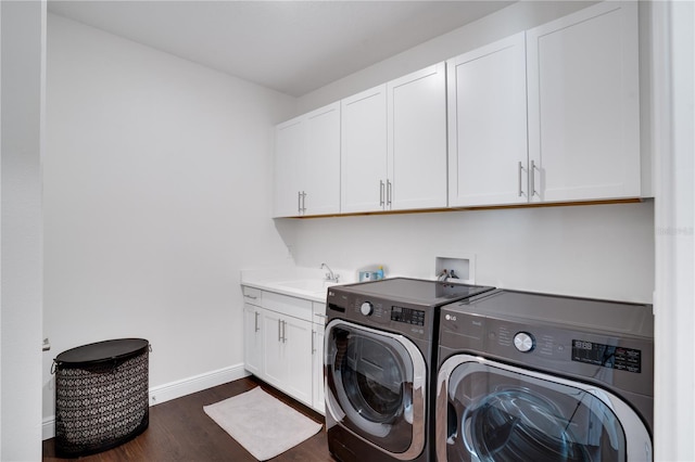 washroom featuring baseboards, dark wood finished floors, a sink, cabinet space, and separate washer and dryer