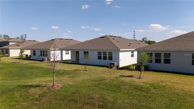 back of house featuring stucco siding, cooling unit, and a yard
