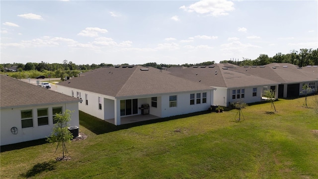 rear view of house featuring roof with shingles, central air condition unit, and a yard