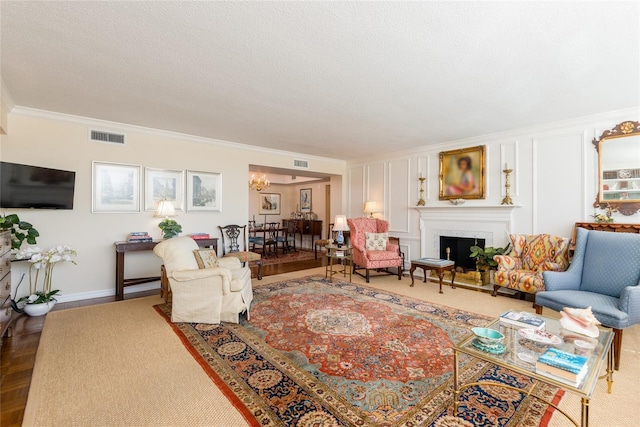 living area with crown molding, visible vents, an inviting chandelier, and a fireplace