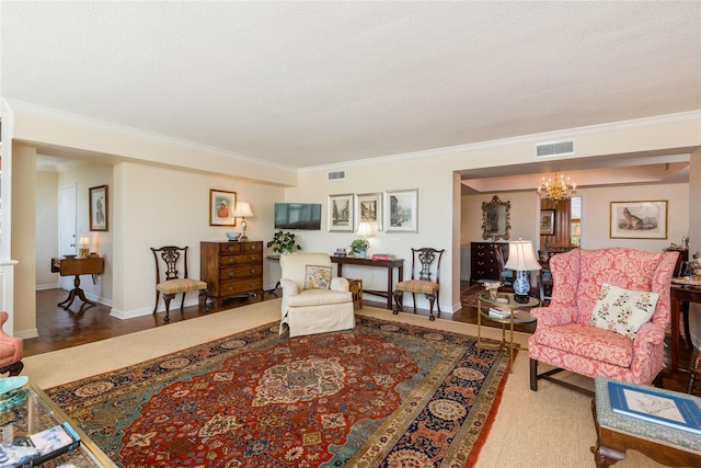 living room with an inviting chandelier, baseboards, ornamental molding, and visible vents