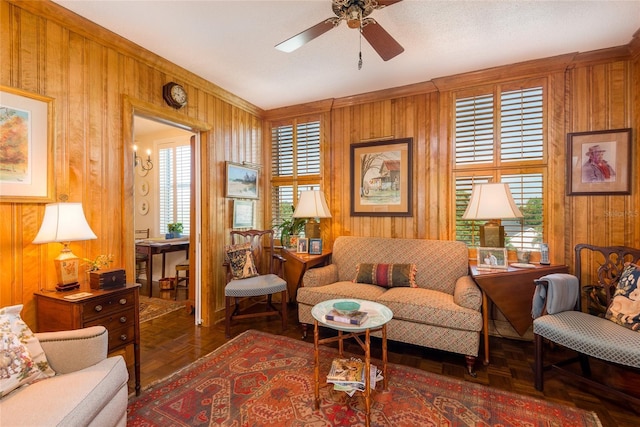 living area with a ceiling fan and wooden walls