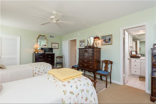 bedroom featuring visible vents, baseboards, ensuite bathroom, light colored carpet, and a ceiling fan