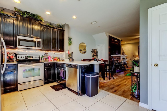 4676 66th Pl N, Pinellas Park, FL 33781 - kitchen with tasteful backsplash, a peninsula, light tile patterned flooring, and appliances with stainless steel finishes
