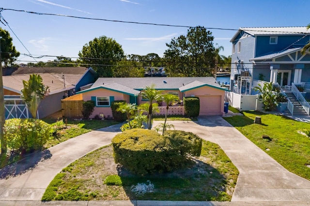 view of front facade featuring stairs, fence, an attached garage, driveway, and a front yard