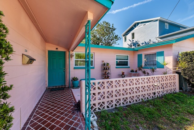 doorway to property with fence and concrete block siding