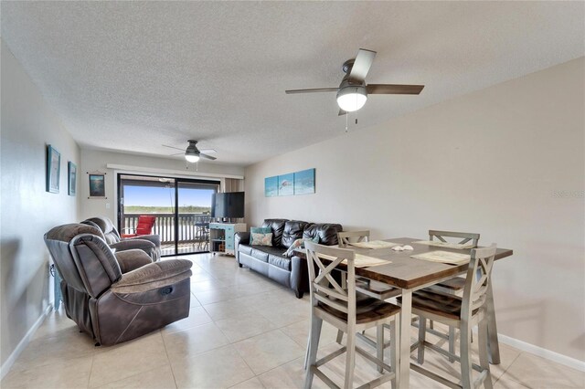 dining space featuring light tile patterned flooring, baseboards, ceiling fan, and a textured ceiling
