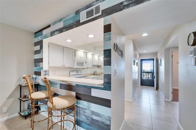 kitchen with light tile patterned floors, visible vents, a sink, and white appliances