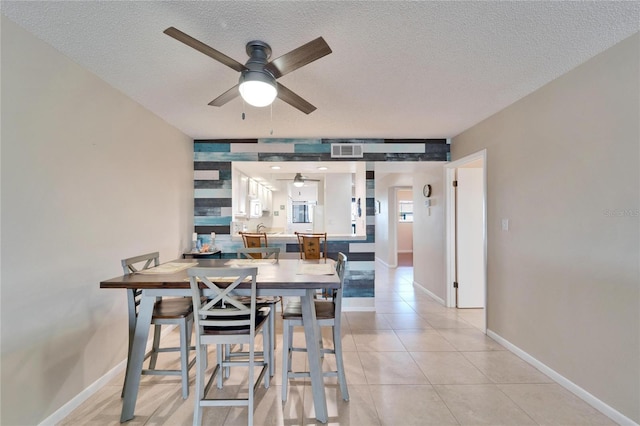 dining area featuring a ceiling fan, a textured ceiling, light tile patterned floors, baseboards, and visible vents