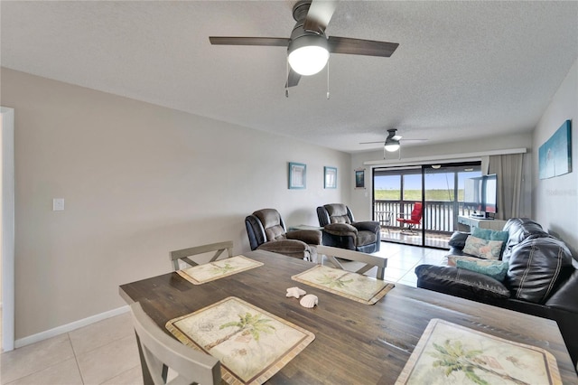 dining area featuring a textured ceiling, ceiling fan, baseboards, and light tile patterned floors