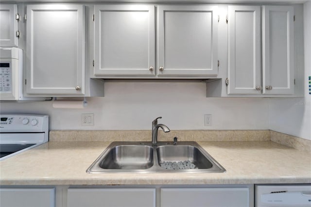 kitchen featuring white appliances, light countertops, and a sink