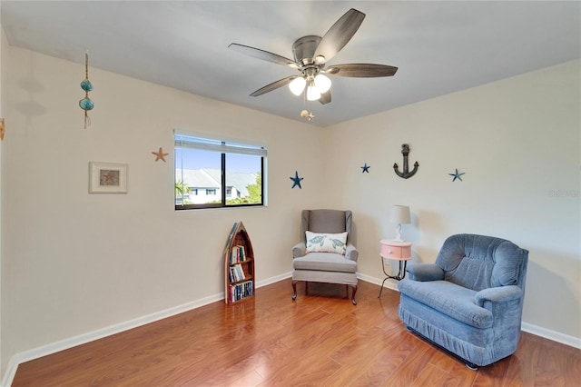 living area featuring baseboards, ceiling fan, and wood finished floors
