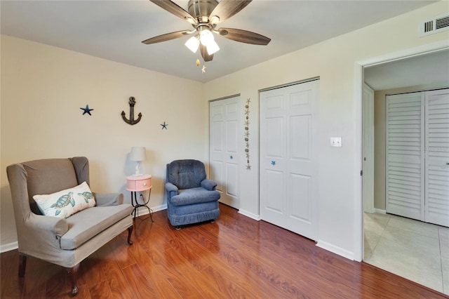 sitting room featuring wood finished floors, baseboards, ceiling fan, and visible vents