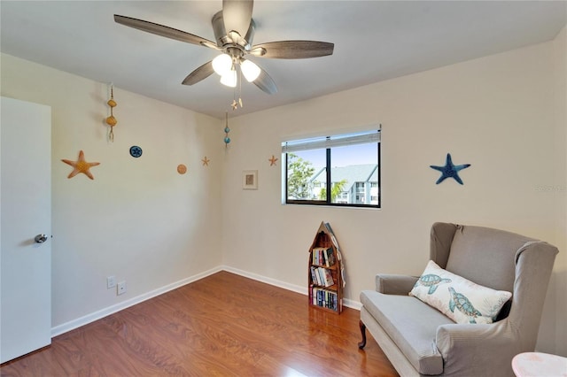 sitting room with a ceiling fan, baseboards, and wood finished floors