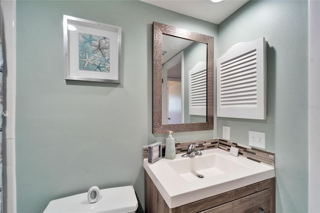 full bath with toilet, decorative backsplash, and vanity