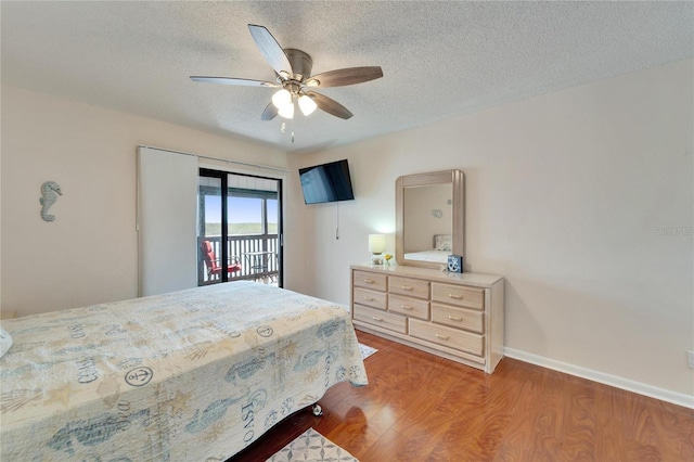 bedroom featuring baseboards, a textured ceiling, access to exterior, a ceiling fan, and wood finished floors